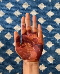 a person's hand painted with red and orange designs on it, in front of a blue background