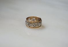 a gold and silver ring with leaves on the inside, sitting on a white surface