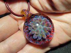 Indulge in the beauty of handcrafted art with these stunning implosion pendants! Each blown glass pendant is meticulously crafted by me, using only the finest quality Borosilicate glass and a blowtorch in my studio. I take great pride in the intricate designs and depth of each pendant, which remind me of the delicate lotus blossoms, succulents or anemones, carefully captured in glass. As a one-of-a-kind creation, each pendant is truly unique and crafted entirely from molten glass.  The pendant has a large glass bail  which also provides flexibility to change the chains and cords for a different look. The pendant comes with a leather cord with a sterling silver lobster claw clasp. I custom-make each leather cord to order and can accommodate different lengths as per your request. I take grea Unique Glass Pendant Jewelry, Spiritual Round Glass Pendant Jewelry, Spiritual Glass Jewelry With Round Pendant, Spiritual Glass Pendant Jewelry, Handmade Spiritual Murano Glass Jewelry, Handmade Czech Glass Round Pendant Jewelry, Handmade Round Jewelry From Recycled Glass, Handmade Clear Flower Pendant Jewelry, Handmade Clear Jewelry With Flower Pendant