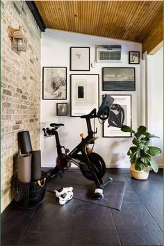 an indoor exercise bike in the corner of a room with pictures on the wall behind it