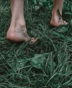 a person standing in the grass with their bare feet