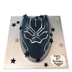 a birthday cake with a black panther mask on it's face and stars around the edges