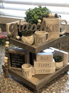 two tiered trays with coffee mugs and signs on them sitting on a counter