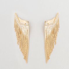 Fringe appliques are accessories that will transform a simple earring into a new, eye-catching, and unparalleled proposition. Once attached behind the ear, this piece will provide movement and charm to the chosen earring.This time, the featured fringe boasts a noble metal structure, gold plated or white rhodium plated, made of gradient-sized chains with an ultra-fine thickness and an ear cuff design.Note: EARRINGS ARE NOT INCLUDED WITH THE ORIGINAL PIECE, IT IS MERELY AN ILLUSTRATION. Gold Single Ear Cuff, Gold Dangle Ear Climber Earring, Elegant Gold Metal Ear Climbers, Gold Fringe Earrings In Brass, Gold Brass Ear Cuff For Parties, Gold Metal Ear Climbers For Pierced Ears, Gold Metal Ear Climbers, Gold Metal Ear Climbers For Party, Gold Plated Ear Cuff For Party