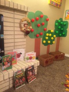 there are many books on display in the room with trees and apples painted on them