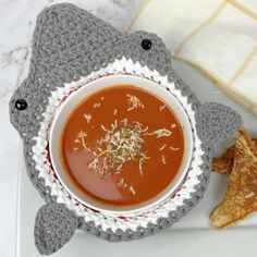 a white plate topped with a bowl of soup next to some tortilla chips