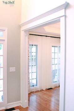 a living room with hard wood floors and white curtains