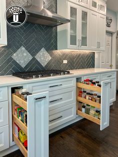 an open cabinet in the middle of a kitchen with white cabinets and wood flooring