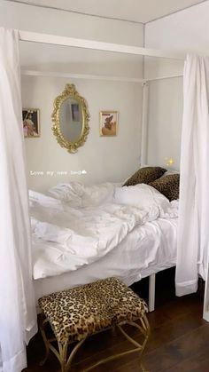 a bed with white sheets and leopard print foot stools in front of the bed