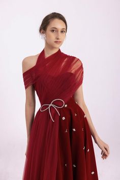 a woman wearing a red dress with an asymmetrical neckline and tulle skirt