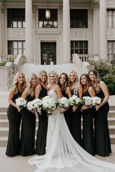 a bride and her bridals posing in front of the stately building at their wedding