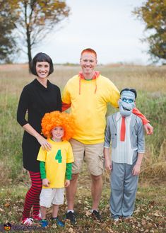 a family dressed up in costumes posing for a photo with their son and daughter, who is wearing an orange wig