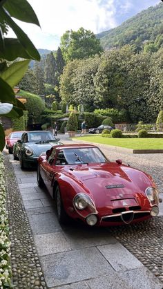 three classic sports cars parked on the side of a road