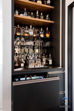 a bar with lots of liquor bottles and glasses on the top shelf in front of it