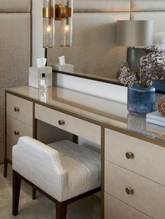 a dressing table with a mirror, stool and lights on it in a room that is well lit