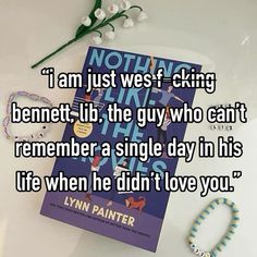 a book and bracelets sitting on top of a white table next to a flower