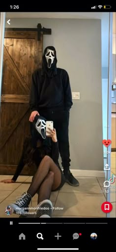 a person in a mask is taking a selfie with their cell phone while wearing a black outfit