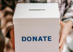 a person holding up a box with the word donation written on it in blue ink