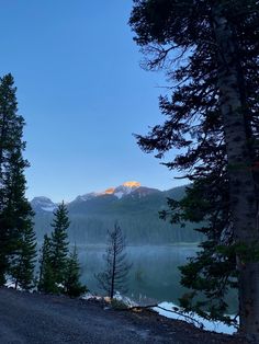 the sun is setting on a mountain lake with pine trees around it and mountains in the distance