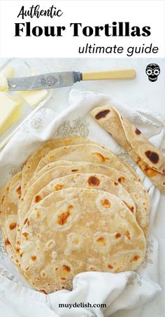 four homemade flour tortillas sitting on top of a white cloth next to butter