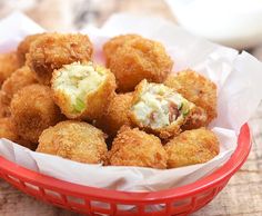 a red basket filled with fried food on top of a wooden table next to a white napkin