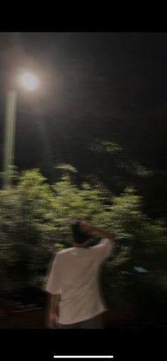 a man standing in front of a street light at night with his back to the camera