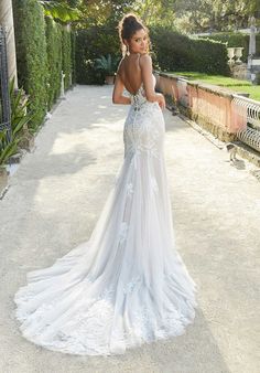 a woman in a wedding dress is standing on the sidewalk and looking at her back