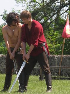 two men with swords standing in the grass