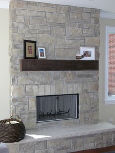 a living room with a stone fireplace and pictures on the mantle