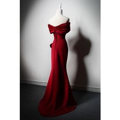 a red evening gown on display in front of a white wall with shadow from the mannequin's head