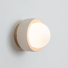 a white wall light mounted on the side of a wall with a round light fixture