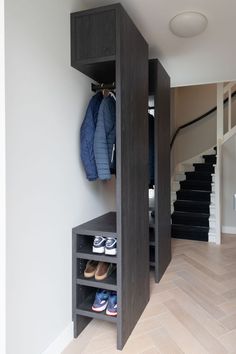 an open closet in the corner of a room with shoes and coats hanging on it