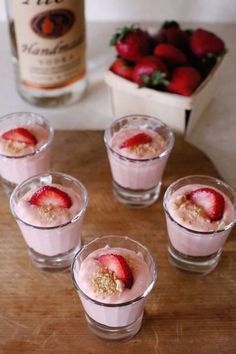 four small glasses filled with food on top of a wooden table next to each other