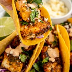 someone is holding up some tacos with meat and vegetables on the plate in front of them