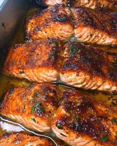 four salmons cooking in a pan with sauce and herbs on the side, ready to be cooked