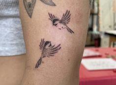 a woman's arm with two small birds on the left side of her body