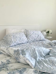 an unmade bed with blue and white comforter on it's headboard