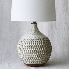 a white ceramic table lamp with a light shade on it's base and a wooden base