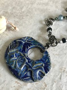 This large Ginko leaf pendant is double sided, with swirls on the reverse. It is glazed front and back, and can be worn with either side out, depending on your preference. The Swarovski glass beads are iridescent. The chain was also handmade by me, including the bail and clasp. This pendant can be removed from the chain so you may wear the pendant with other chains, the chain by itself, or the chain with another pendant. This statement necklace was made by me in my studio. Beginning with raw cla Artistic Blue Beaded Necklace, Artistic Blue Jewelry With Large Pendant, Artisan Blue Hand Painted Necklaces, Artisan Hand Painted Blue Necklaces, Artisan Hand Painted Blue Necklace, Artsy Nickel-free Blue Jewelry, Artsy Blue Nickel-free Jewelry, Artistic Blue Beaded Jewelry, Artsy Blue Round Pendant Jewelry