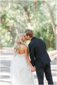 a bride and groom kissing in front of trees