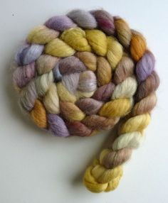 a close up of a wool roving on a white surface with the top spinning