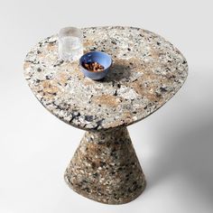 a small table with a bowl on it and a glass in the middle sitting on top