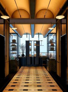 an empty hallway with black and white tiles on the floor in front of large windows