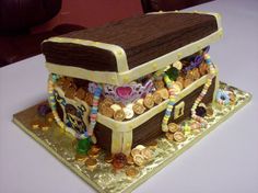 a cake made to look like a trunk with coins on it and beads around the top