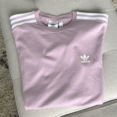 Adidas Originals T-Shirt In Like-New Condition, Never Worn Logo On Heart And On Sleeve With Stripes On Shoulders Light Pinkish-Purple Pastel Colorway Heather Cotton Streetwear Top, Heather Cotton Top For Streetwear, Sporty Purple Tops With Graphic Print, Spring Lavender Letter Print Top, Purple Graphic Print Tops For Loungewear, Lavender Top For Spring Streetwear, Purple Crew Neck Top With Letter Print, Purple Letter Print Crew Neck Top, Purple Graphic Tee With Relaxed Fit