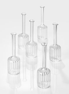 six clear glass vases are lined up in a row