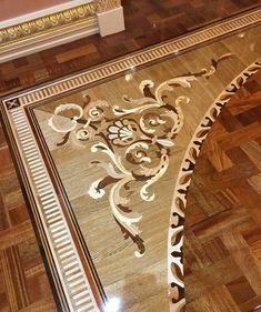 an intricately designed glass table in a room with wood flooring and gold trimmings