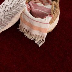 two baskets with towels and blankets are on the floor in front of a red carpet