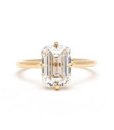 an emerald cut diamond engagement ring with two shoulders and three prongs on the band