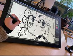 someone is drawing on an electronic device with a pen in their hand and the screen has a cartoon character drawn on it